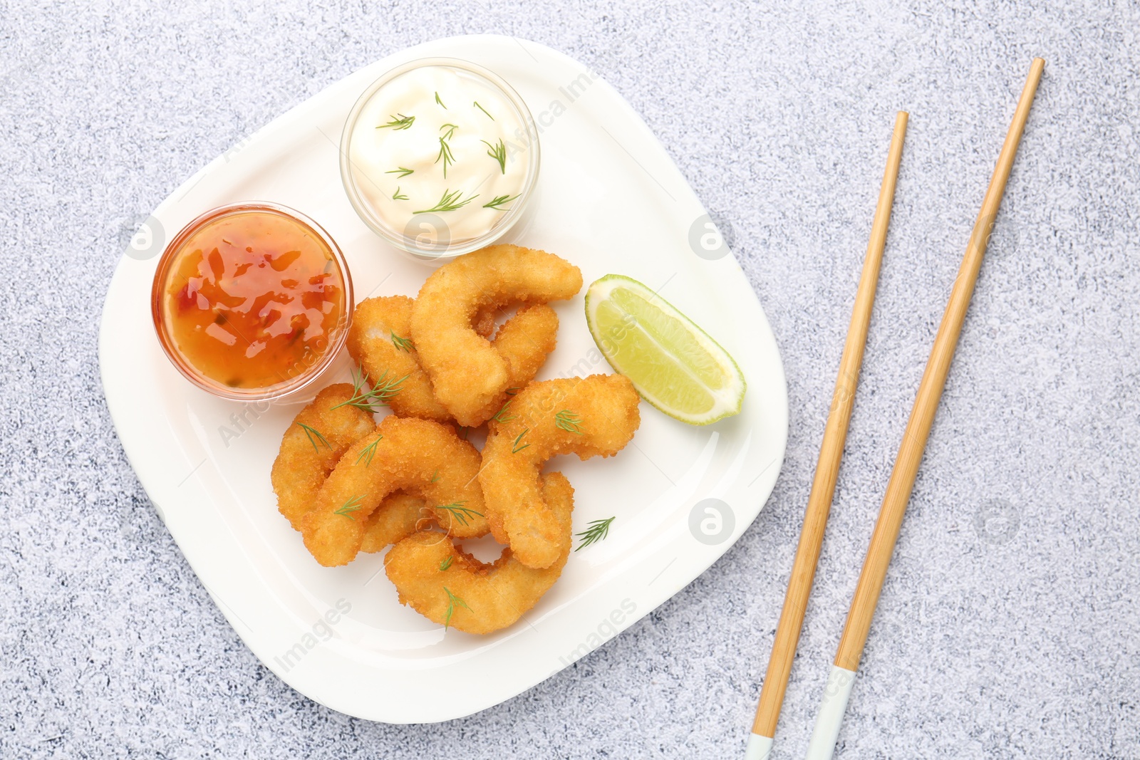 Tasty tempura shrimps, lime, sauces and chopsticks on grey textured table, flat lay Photo of Tasty tempura shrimps, lime, sauces and chopsticks on grey textured table, flat lay