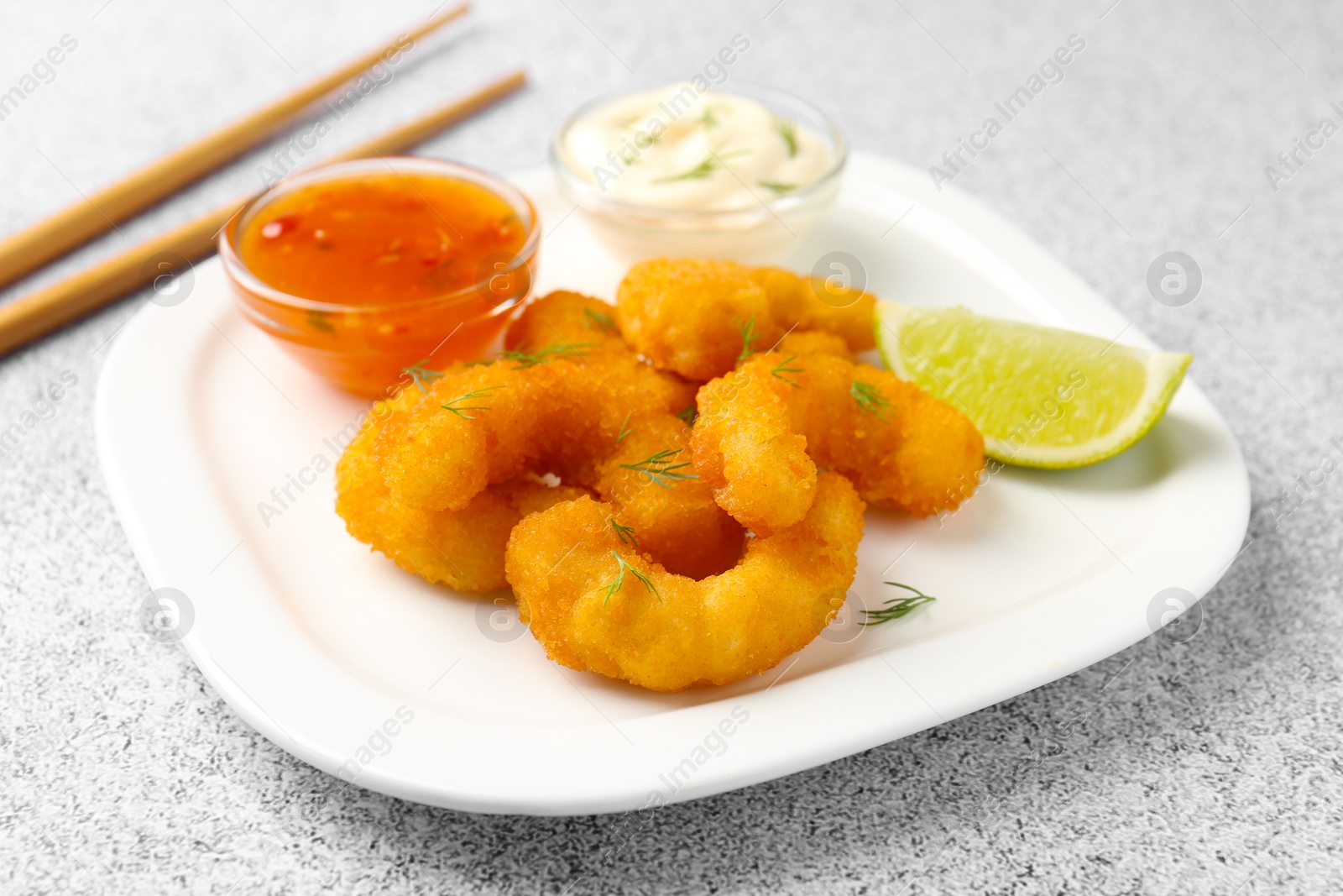 Tasty tempura shrimps, lime and sauces on grey textured table, closeup Photo of Tasty tempura shrimps, lime and sauces on grey textured table, closeup
