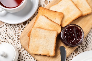 Photo of Slices of tasty toasted bread, jam and cup of tea on table, flat lay
