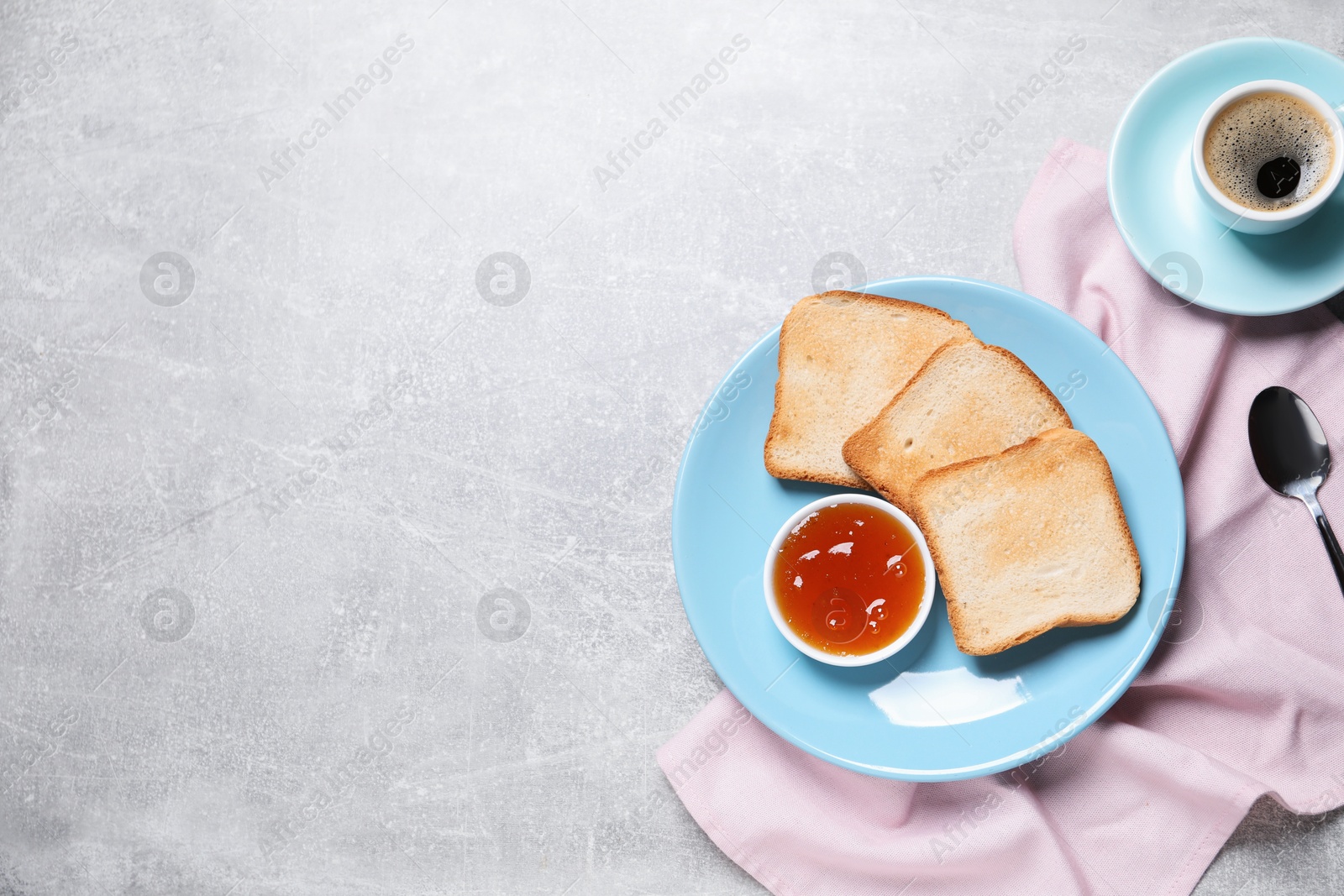 Slices of tasty toasted bread, jam and cup of coffee on grey textured table, flat lay. Space for text Photo of Slices of tasty toasted bread, jam and cup of coffee on grey textured table, flat lay. Space for text