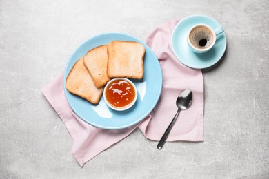 Photo of Slices of tasty toasted bread, jam and cup of coffee on grey textured table, flat lay