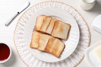 Photo of Slices of tasty toasted bread and cup of tea on white wooden table, flat lay