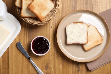 Photo of Slices of tasty toasted bread, butter and jam on wooden table, flat lay