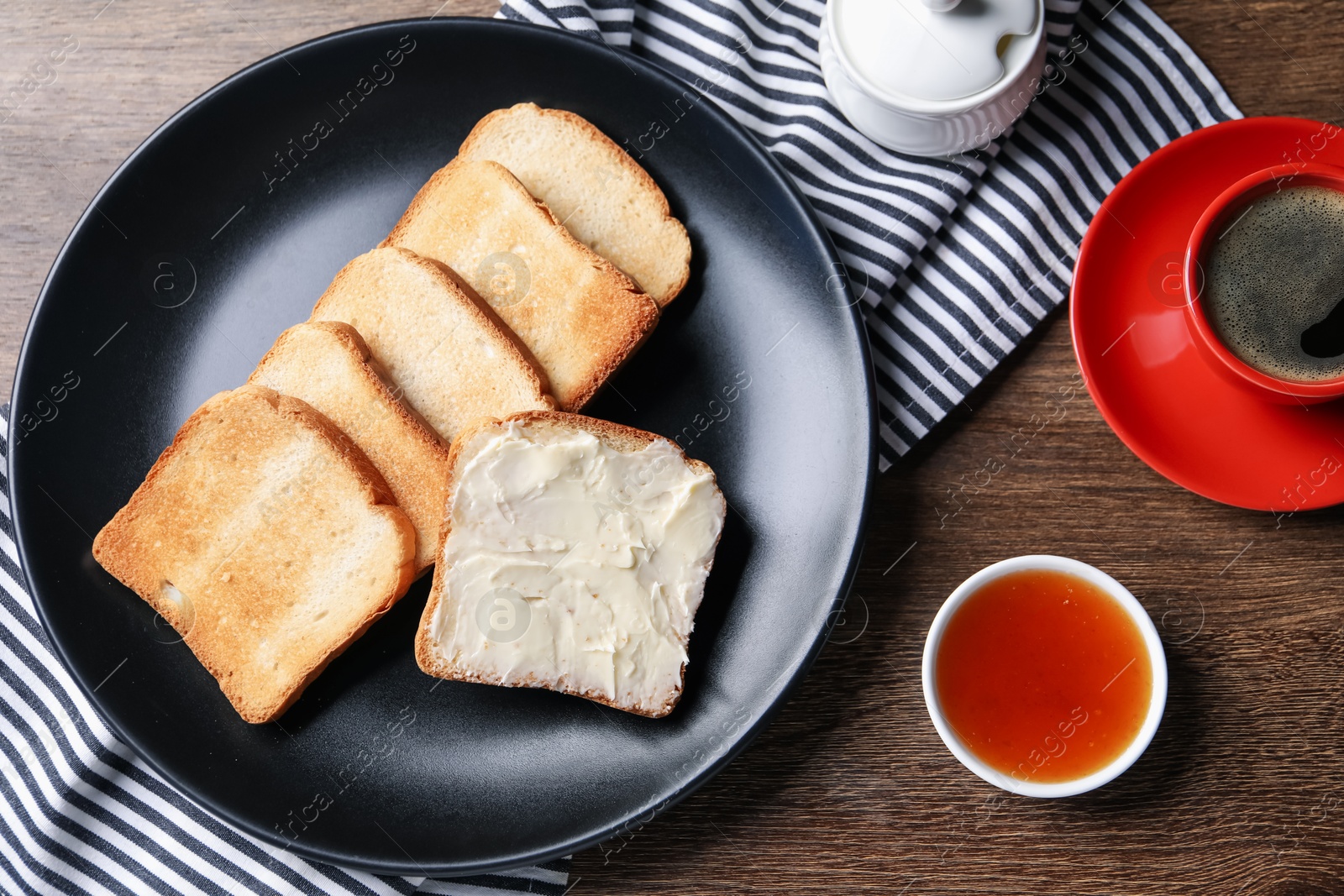 Slices of tasty toasted bread with butter and jam on wooden table, flat lay Photo of Slices of tasty toasted bread with butter and jam on wooden table, flat lay