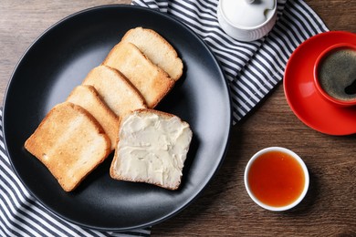 Photo of Slices of tasty toasted bread with butter and jam on wooden table, flat lay