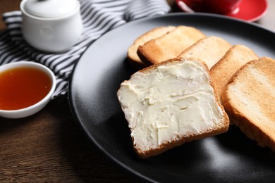 Photo of Slices of tasty toasted bread with butter and jam on wooden table, closeup