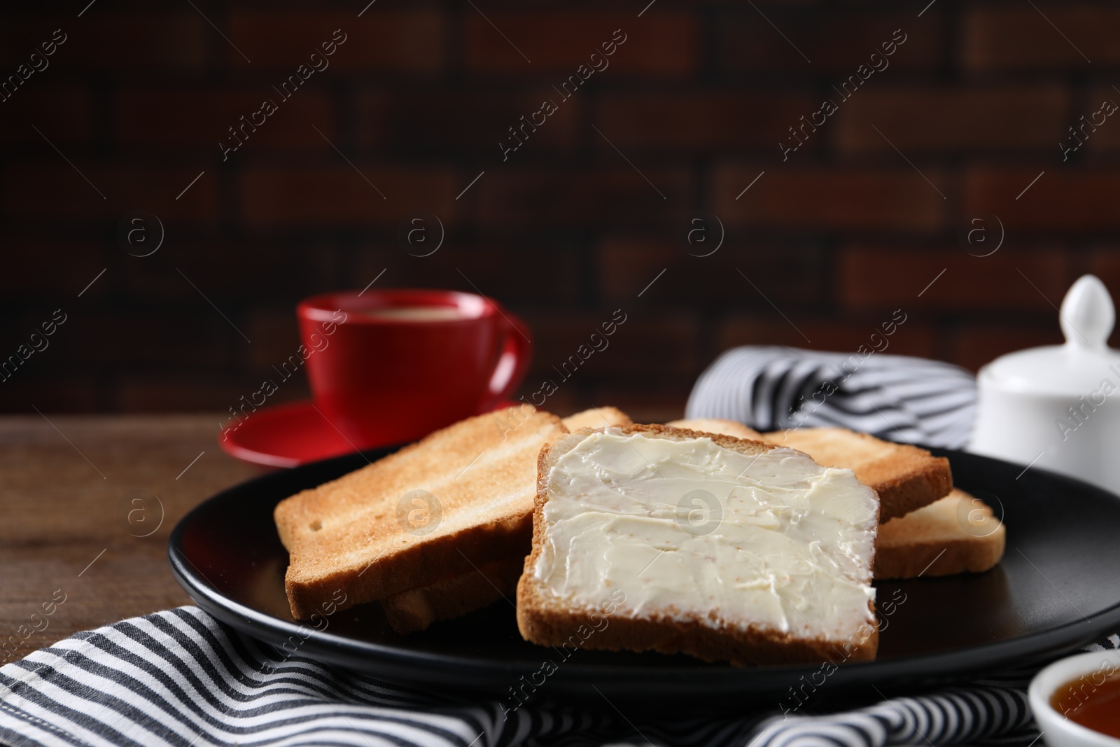 Slices of tasty toasted bread with butter on wooden table against dark background, closeup Photo of Slices of tasty toasted bread with butter on wooden table against dark background, closeup