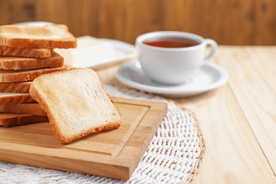 Photo of Slices of tasty toasted bread on wooden table, closeup. Space for text