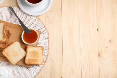 Photo of Slices of tasty toasted bread and jam on wooden table, flat lay. Space for text