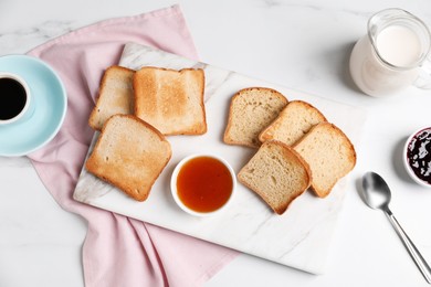 Photo of Slices of tasty toasted bread and jam on white marble table, flat lay