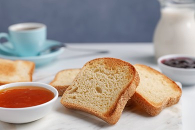 Photo of Slices of tasty toasted bread and jam on white table against grey background, closeup