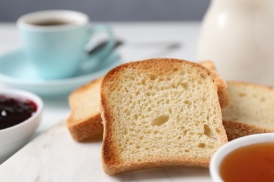 Photo of Slices of tasty toasted bread and jam on white table against grey background, closeup
