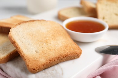 Photo of Slices of tasty toasted bread and jam on white marble board, closeup
