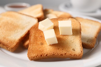Photo of Slices of tasty toasted bread with butter on plate, closeup