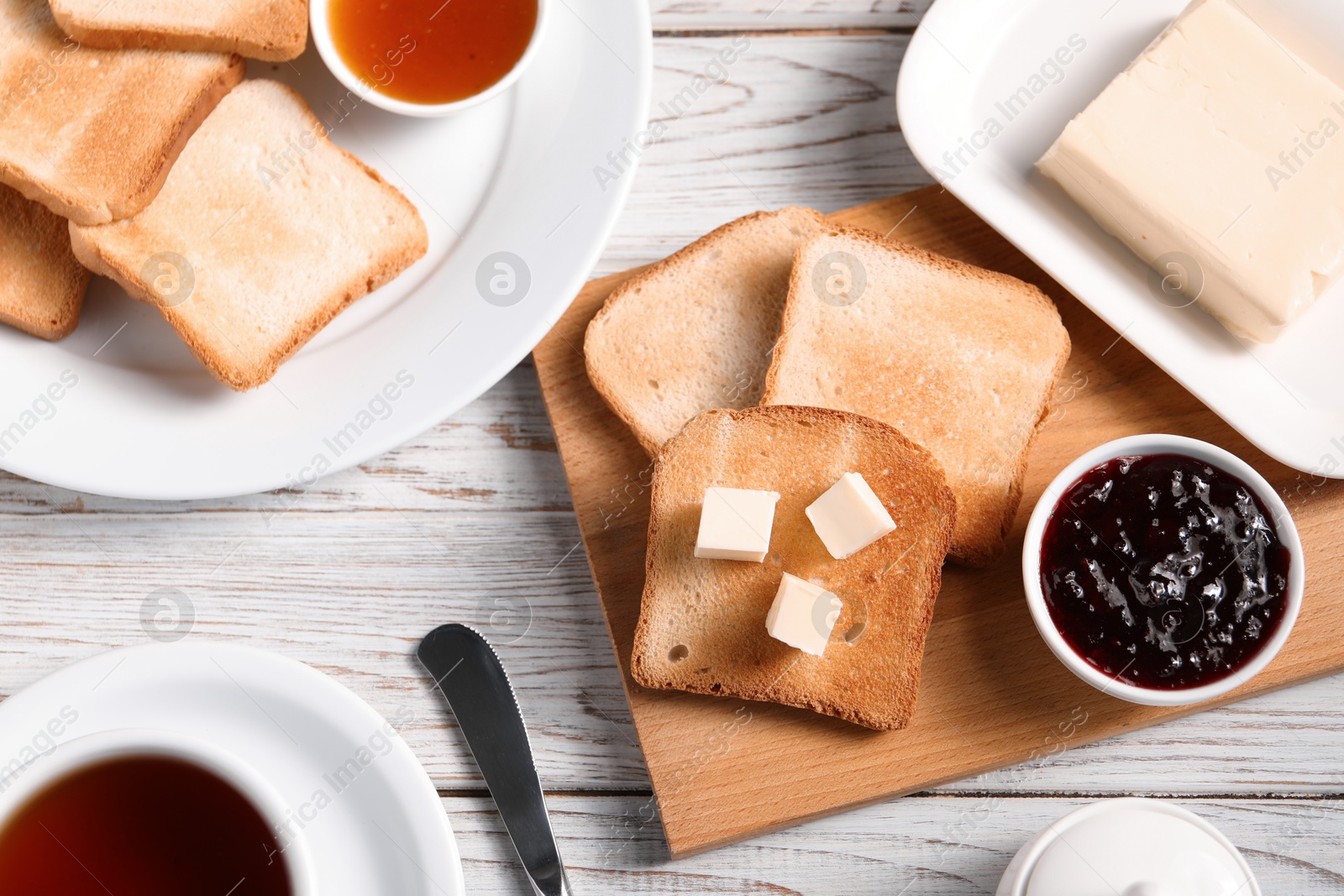 Slices of tasty toasted bread with butter and jam on light wooden table, flat lay Photo of Slices of tasty toasted bread with butter and jam on light wooden table, flat lay