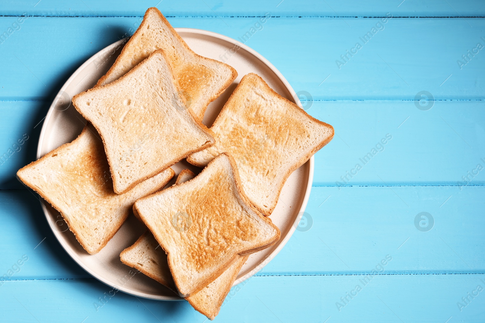 Slices of tasty toasted bread on light blue wooden table, top view. Space for text Photo of Slices of tasty toasted bread on light blue wooden table, top view. Space for text