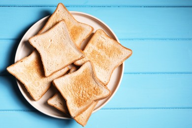 Photo of Slices of tasty toasted bread on light blue wooden table, top view. Space for text