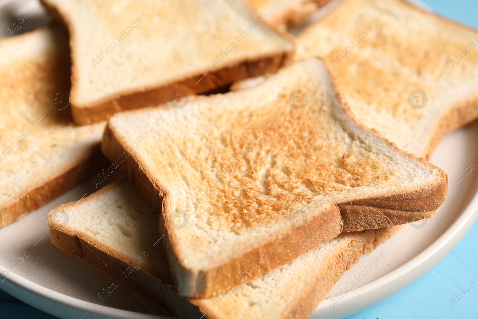 Slices of tasty toasted bread on light blue table, closeup Photo of Slices of tasty toasted bread on light blue table, closeup