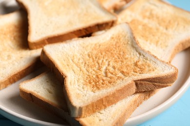 Photo of Slices of tasty toasted bread on light blue table, closeup