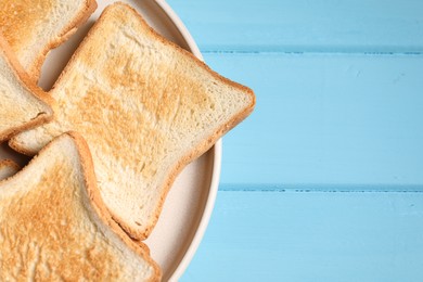 Photo of Slices of tasty toasted bread on light blue wooden table, top view. Space for text