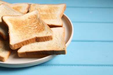 Photo of Slices of tasty toasted bread on light blue wooden table, closeup. Space for text