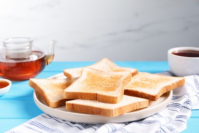Photo of Slices of tasty toasted bread on light blue wooden table against grey background, closeup