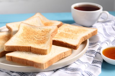 Photo of Slices of tasty toasted bread and jam on light blue table against grey background, closeup