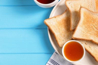 Photo of Slices of tasty toasted bread and jam on light blue wooden table, flat lay. Space for text