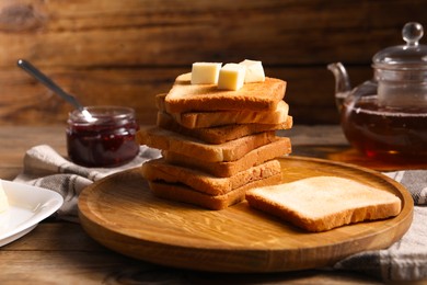Photo of Slices of tasty toasted bread with butter on wooden table, closeup