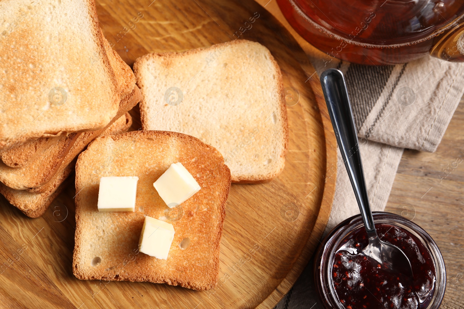Slices of tasty toasted bread with butter and jam on wooden table, flat lay Photo of Slices of tasty toasted bread with butter and jam on wooden table, flat lay