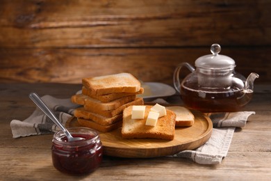 Photo of Slices of tasty toasted bread with butter and jam on wooden table