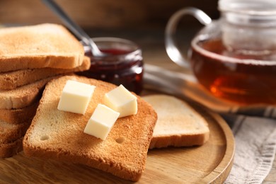 Photo of Slices of tasty toasted bread with butter on table, closeup