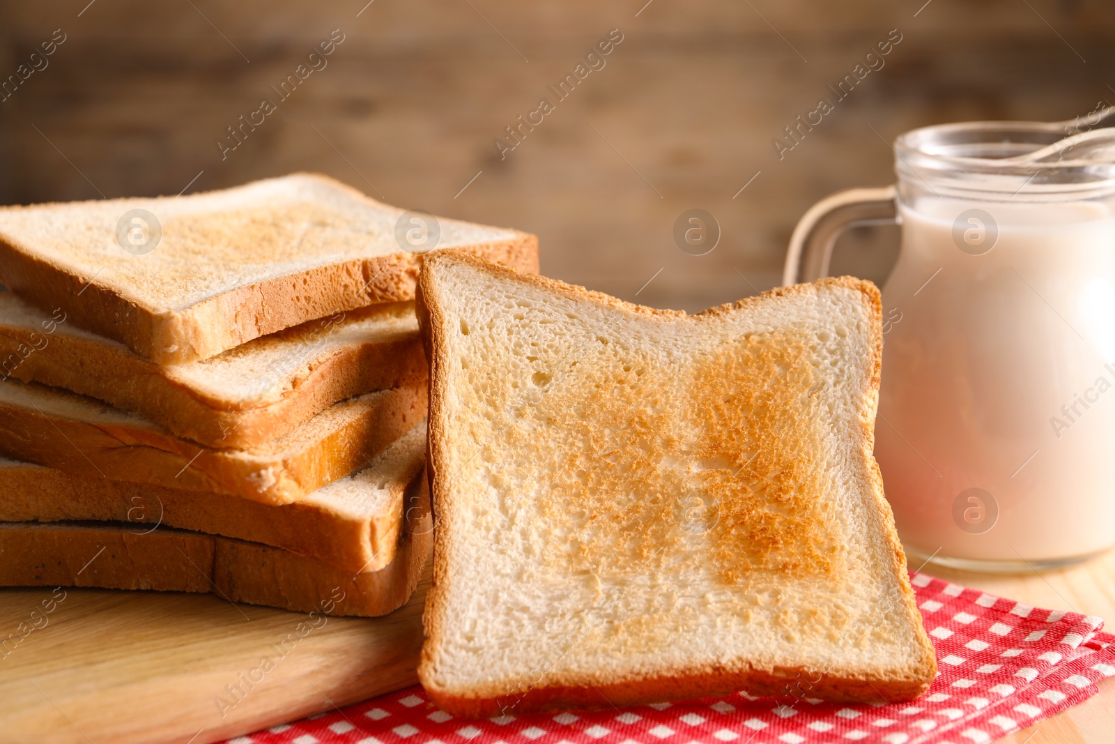 Slices of tasty toasted bread and jug of milk on wooden table, closeup Photo of Slices of tasty toasted bread and jug of milk on wooden table, closeup