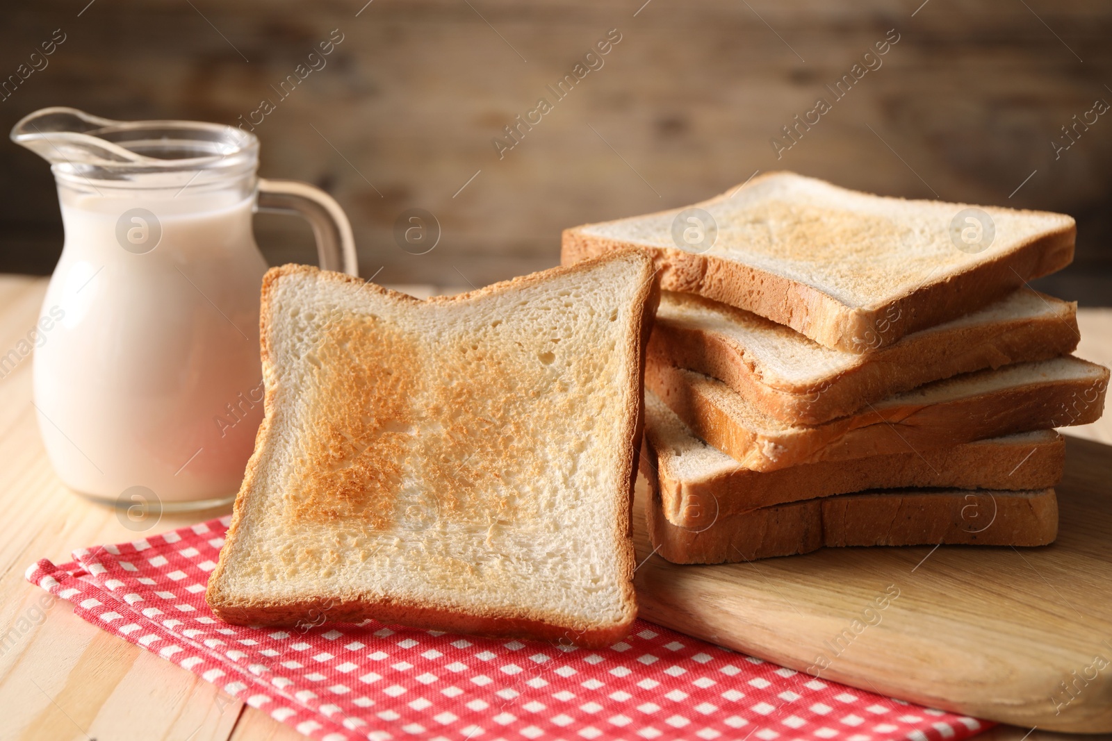 Slices of tasty toasted bread and jug of milk on wooden table, closeup Photo of Slices of tasty toasted bread and jug of milk on wooden table, closeup