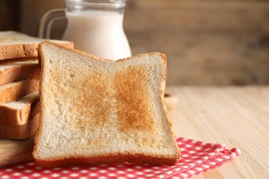 Photo of Slices of tasty toasted bread on wooden table, closeup. Space for text