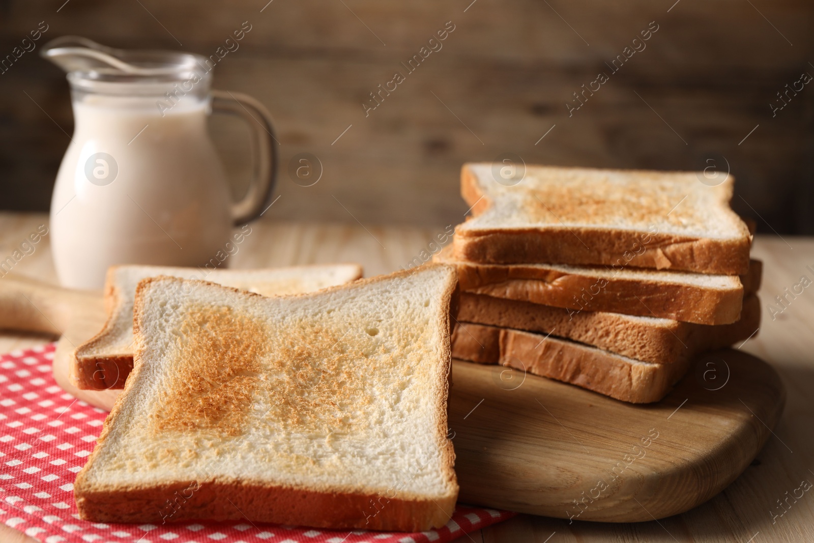 Slices of tasty toasted bread and jug of milk on wooden table, closeup Photo of Slices of tasty toasted bread and jug of milk on wooden table, closeup