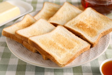 Photo of Slices of tasty toasted bread on checkered tablecloth, closeup