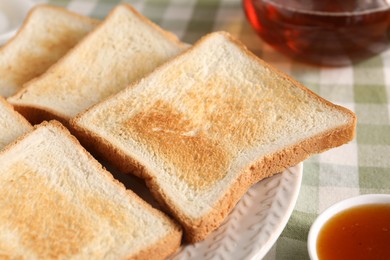 Photo of Slices of tasty toasted bread and jam on checkered tablecloth, closeup