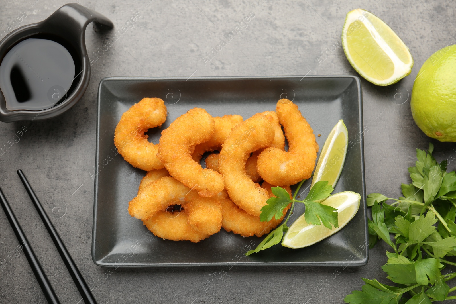 Tasty tempura shrimps, lime, parsley and soy sauce on grey textured table, flat lay Photo of Tasty tempura shrimps, lime, parsley and soy sauce on grey textured table, flat lay