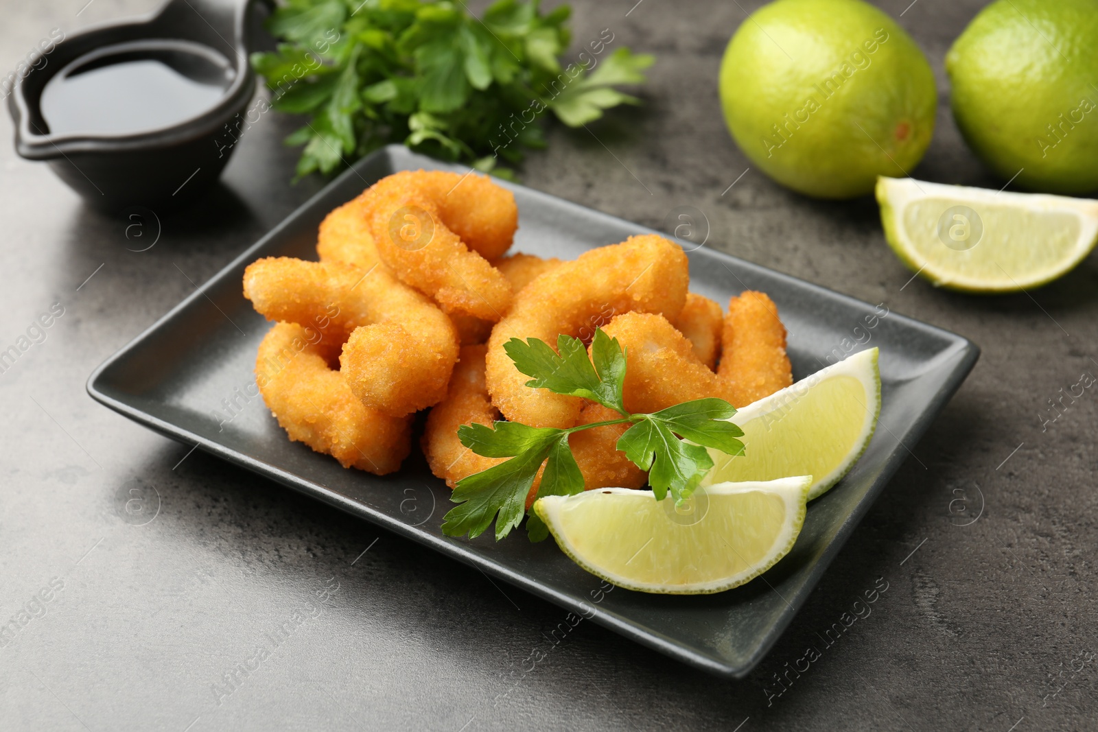 Tasty tempura shrimps, lime, parsley and soy sauce on grey textured table Photo of Tasty tempura shrimps, lime, parsley and soy sauce on grey textured table