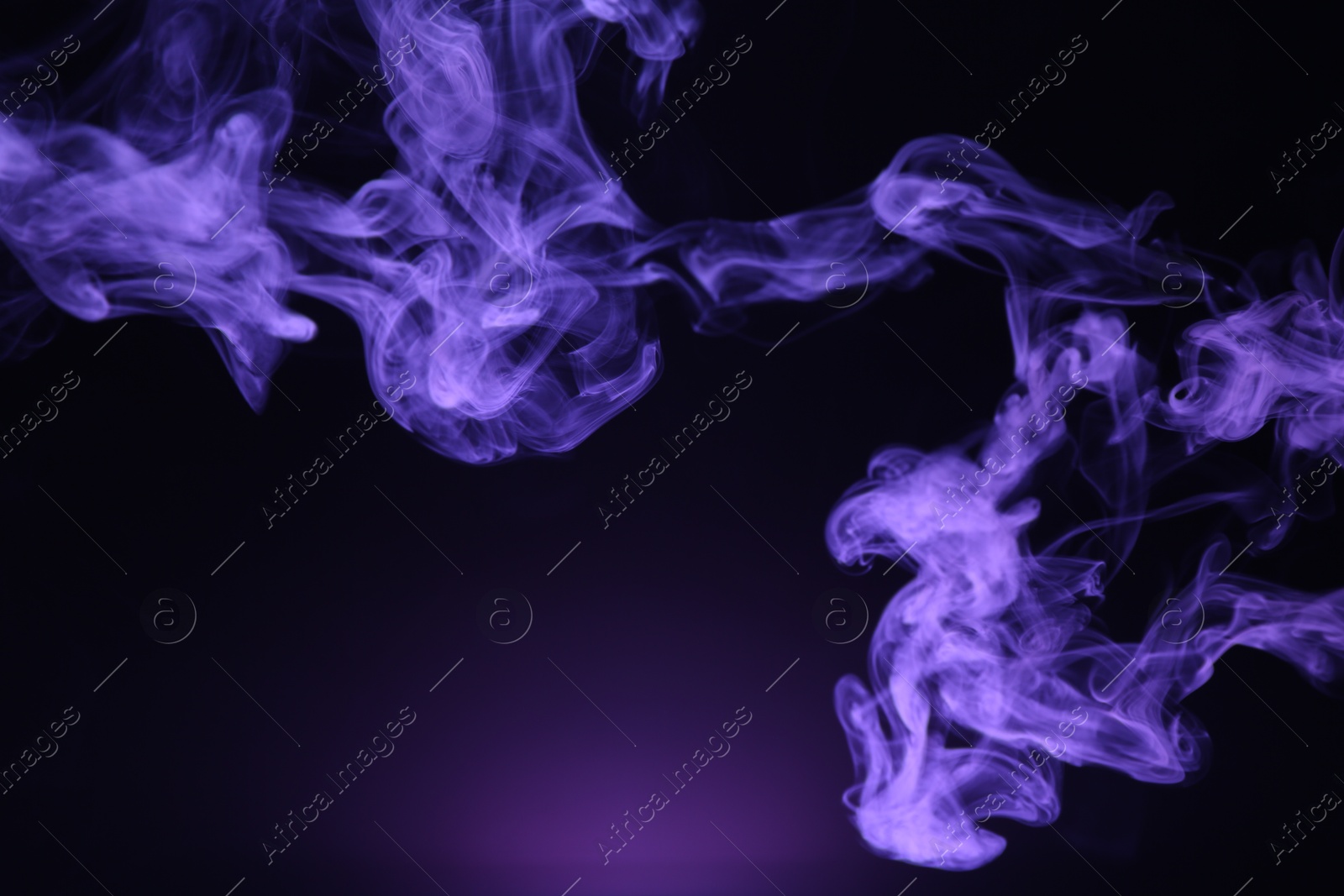 Beautiful smoke in purple light on dark background Photo of Beautiful smoke in purple light on dark background
