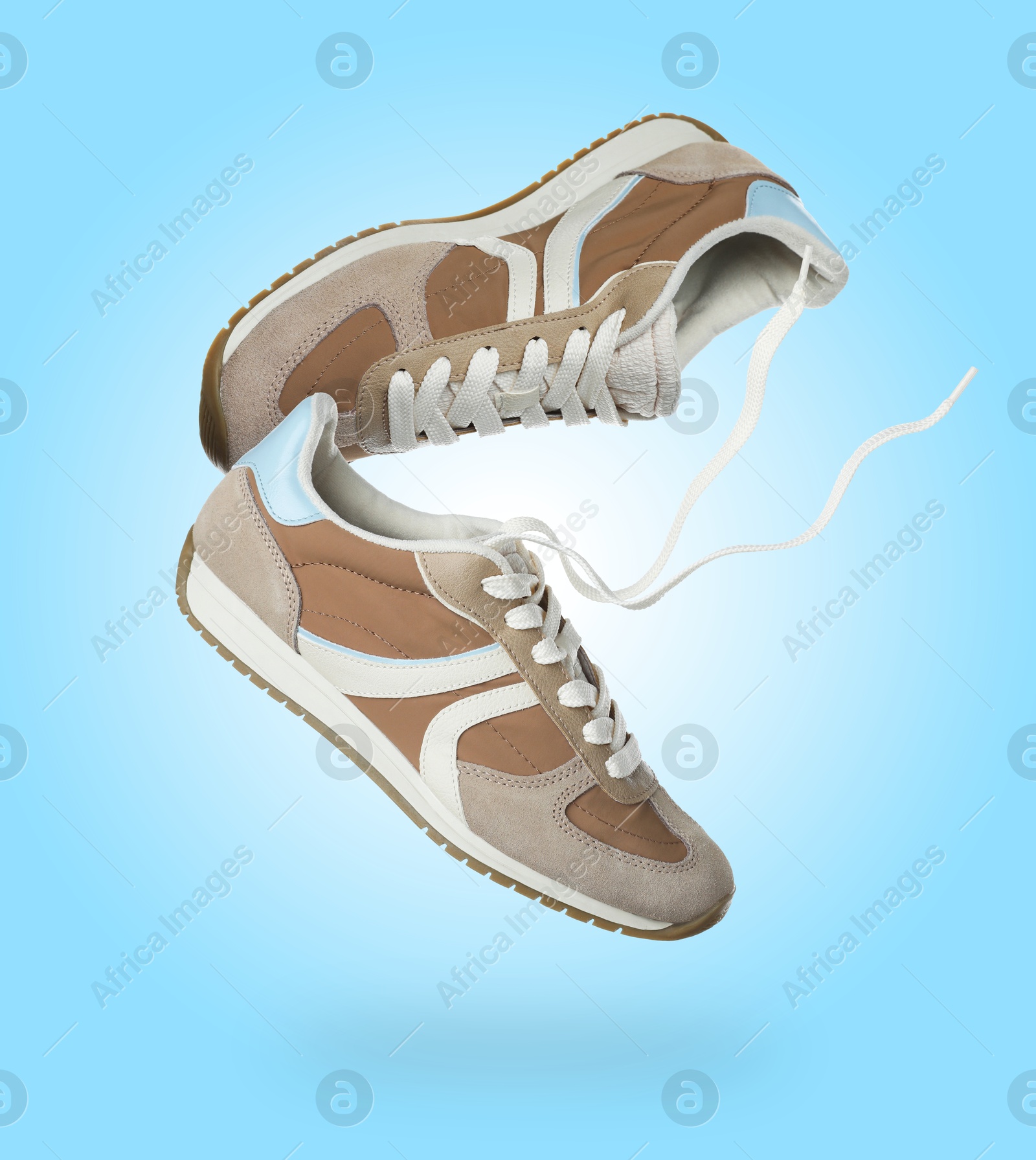 Stylish sneakers in air on light blue gradient background Image of Stylish sneakers in air on light blue gradient background