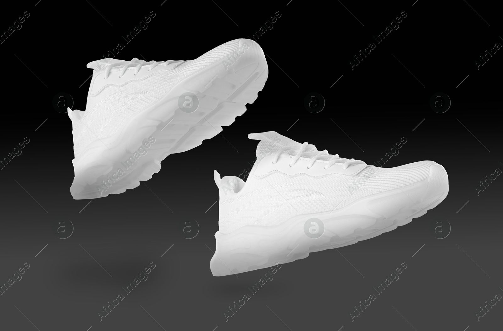 Stylish white sneakers in air on black gradient background Image of Stylish white sneakers in air on black gradient background