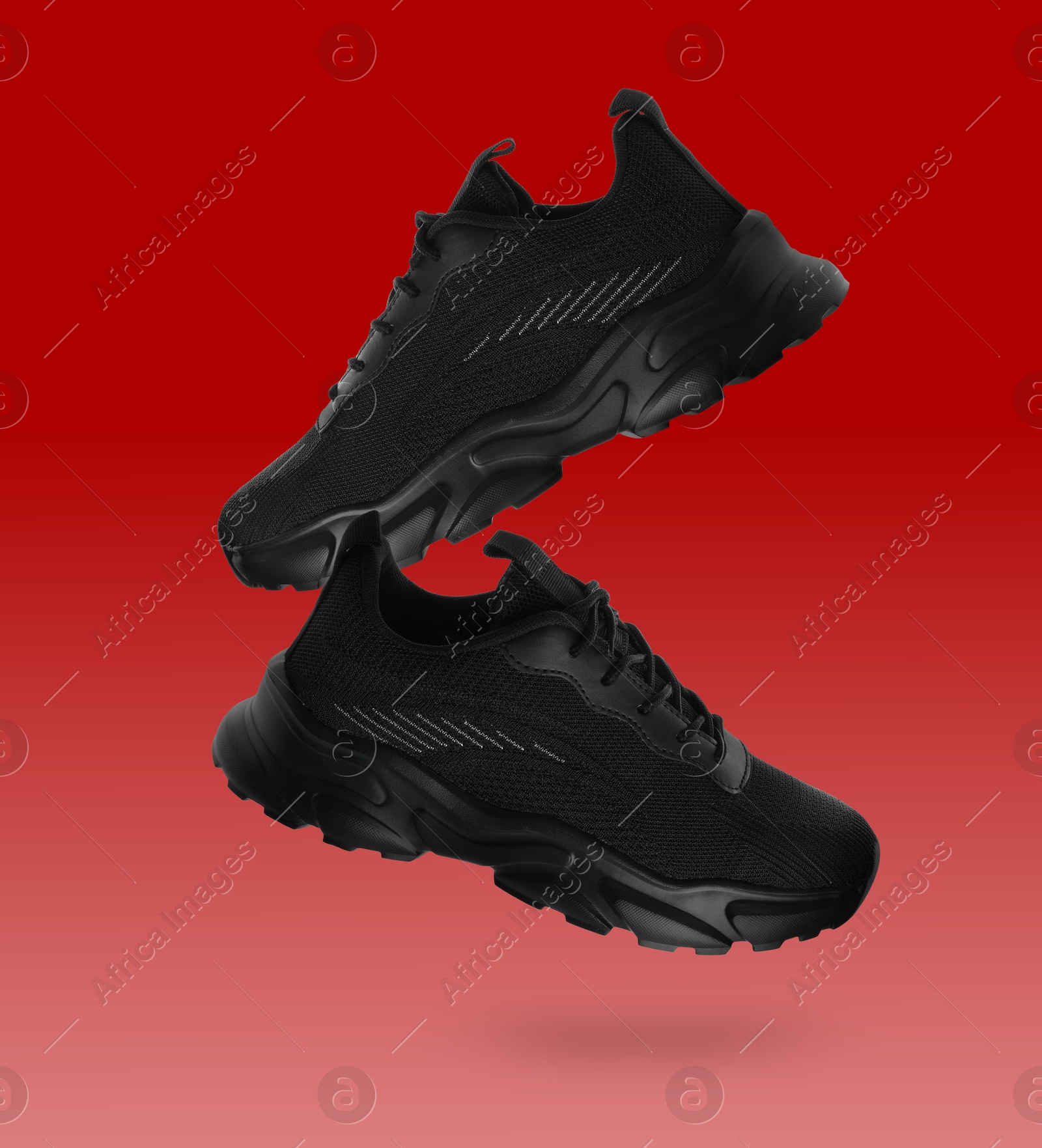 Stylish black sneakers in air on red gradient background Image of Stylish black sneakers in air on red gradient background