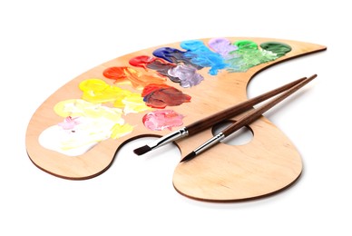Photo of Wooden palette with paints and brushes isolated on white