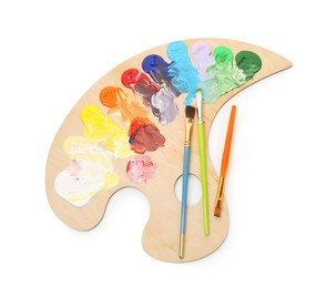 Photo of Wooden palette with paints and brushes isolated on white, top view