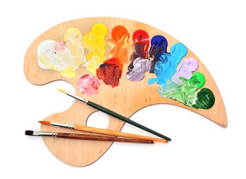 Photo of Wooden palette with paints and brushes isolated on white, top view