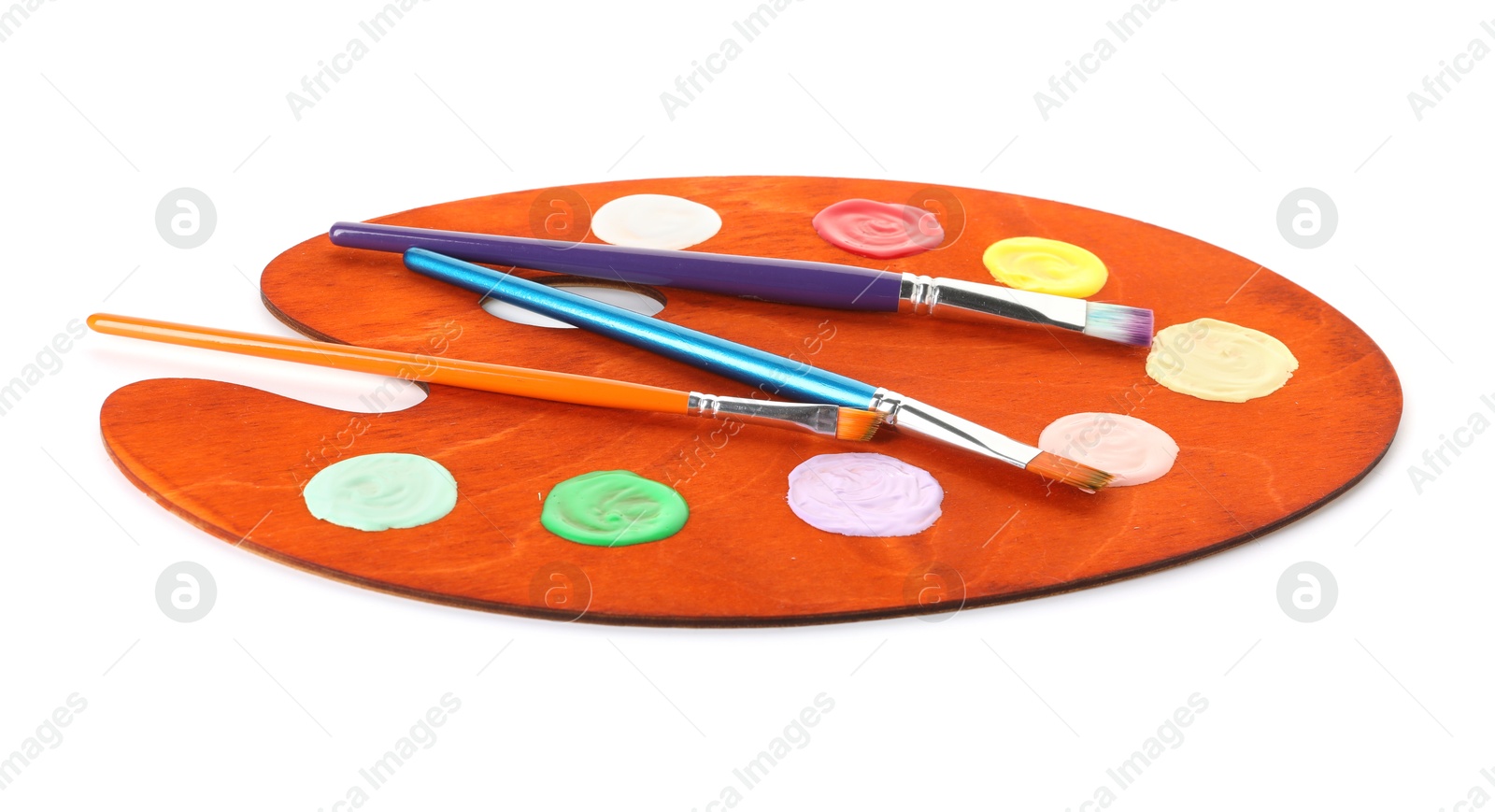 Photo of Wooden palette with paints and brushes isolated on white