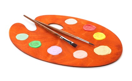 Photo of Wooden palette with paints and brushes isolated on white
