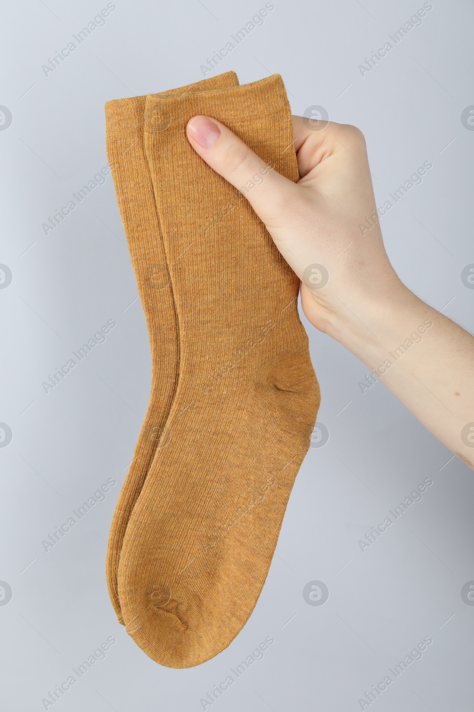 Woman with pair of socks on light grey background, closeup Photo of Woman with pair of socks on light grey background, closeup